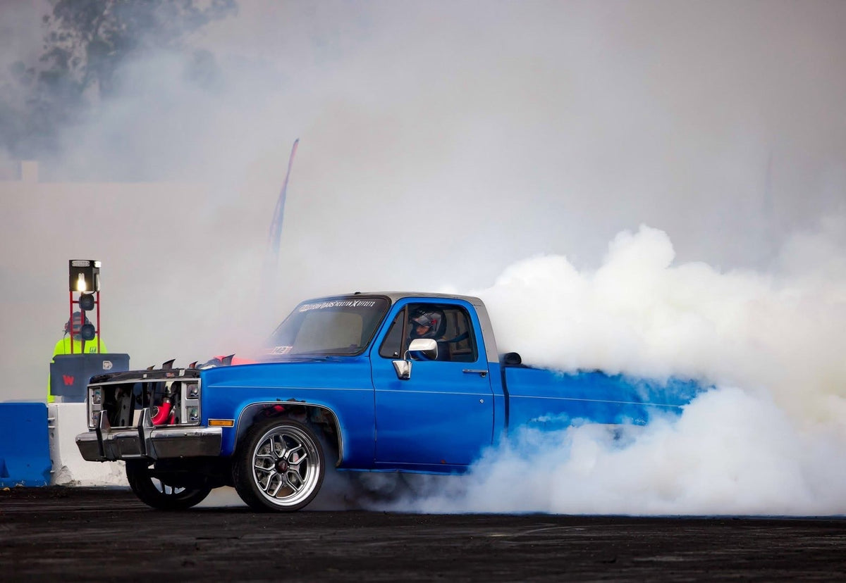 Blue squarebody mid-burnout with the crew's gear staged behind it