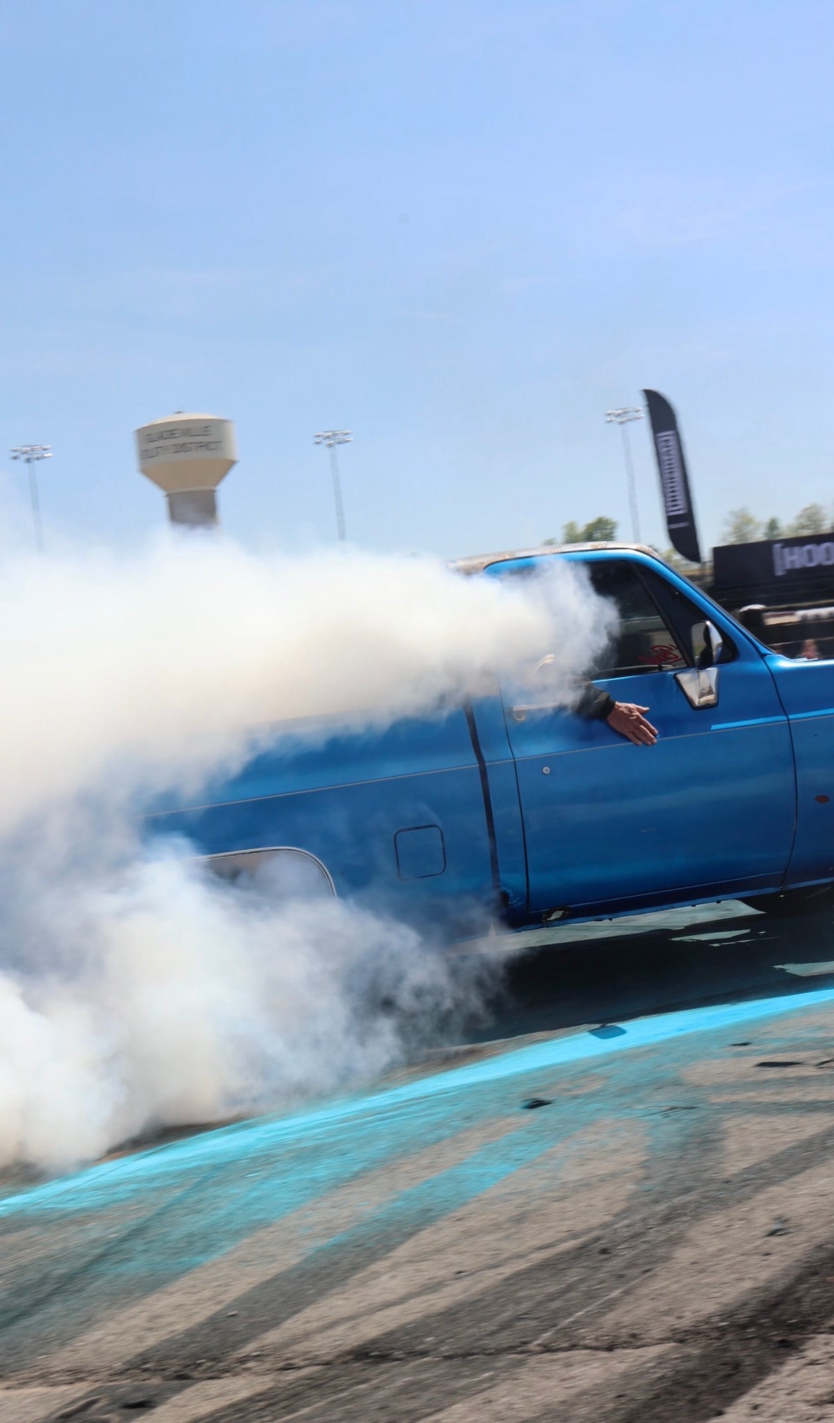 Blue C10 rolling coal, cab wrapped in tire smoke
