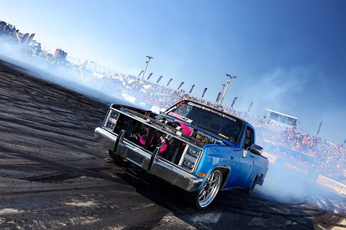 Boosted Brat squarebody laying down a burnout in front of packed grandstands